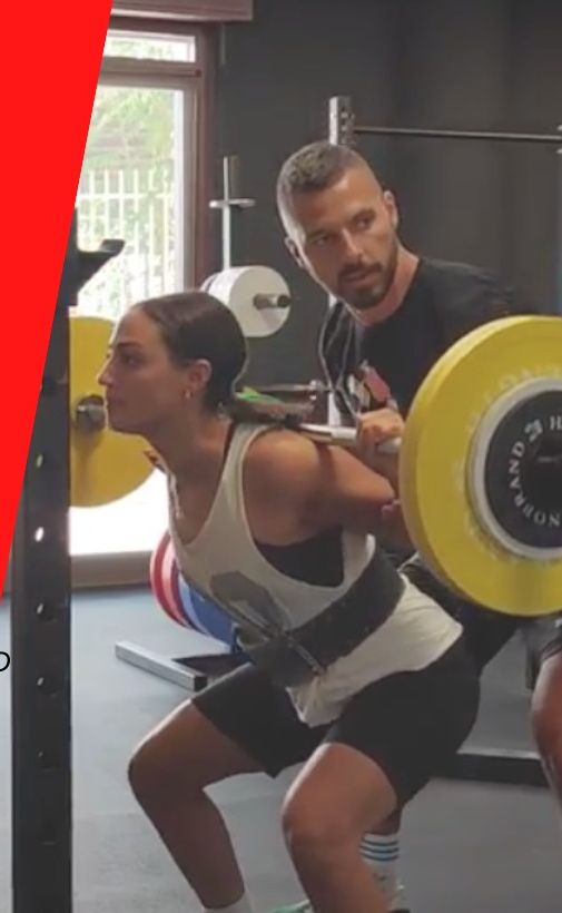 Un coach segue un'atleta durante uno squat in un percorso di personal training